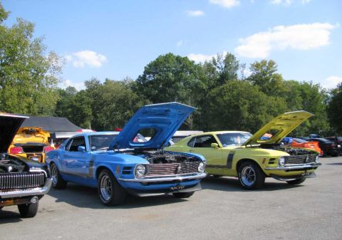 2003 Mercury Marauder - Two classic Ford Mustangs, a blue one and a yellow one, are displayed with their hoods up at an outdoor event.