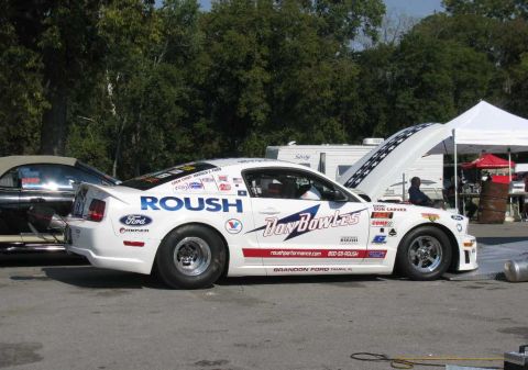 2003 Mercury Marauder - A white Ford Mustang drag car with racing decals is parked outdoors, with its hood open, next to another vehicle.