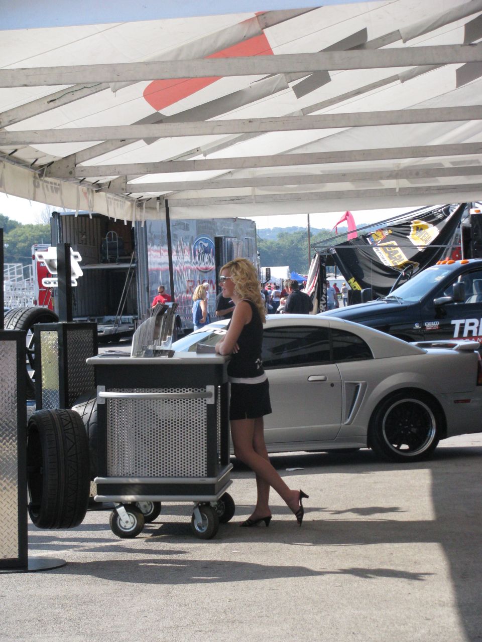 Silver Ford Mustang coupe with black wheels parked next to a black truck