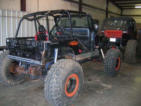 1992 Ford Mustang - Two modified Jeeps are parked indoors, one with a prominent roll cage and off-road tires.