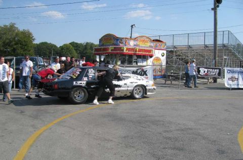 2003 Mercury Marauder - Cars are being pushed into position at a drag racing event with spectators and a food stand present.