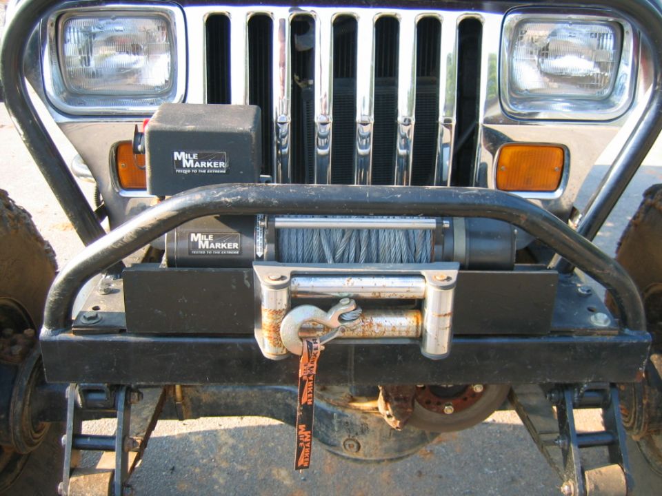 Front view of a weathered Jeep Wrangler with a Mile Marker winch mounted on a black bull bar