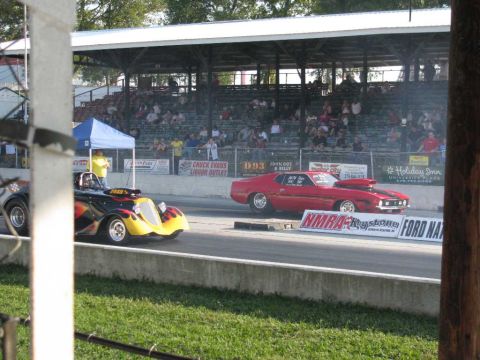 2003 Mercury Marauder - Drag cars compete on a sunny day at a race track with grandstands full of spectators.