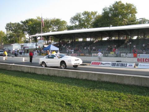 2003 Mercury Marauder - A white 1999 Ford Mustang is captured mid-race with its front wheels lifted off the drag strip.