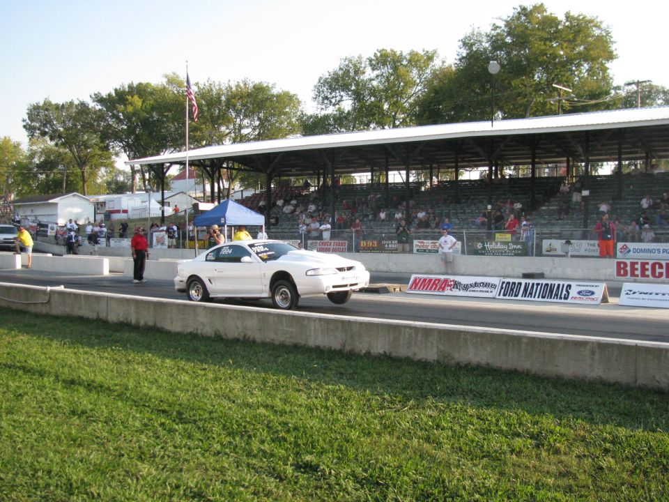 White 1999 Ford Mustang drag racing, front wheels off the ground