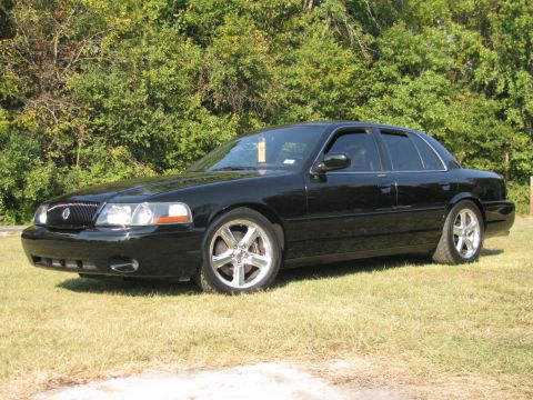 2003 Mercury Marauder - A black 2003 Mercury Marauder sedan is seen from a three-quarter front view, parked on a grassy area with trees in the background.