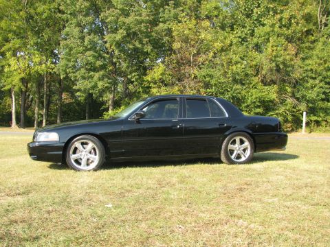 2003 Mercury Marauder - A black 2003 Mercury Marauder is shown from the side, parked on a grassy area with trees behind it.