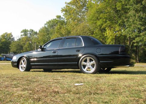 2003 Mercury Marauder - A black 2003 Mercury Marauder is shown from the rear quarter angle, parked on a grassy area with trees in the background.
