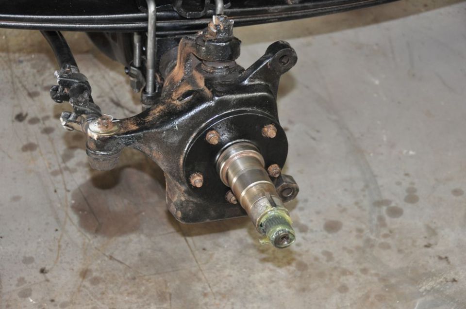 Black metal front wheel hub and steering knuckle assembly with grease on spindle