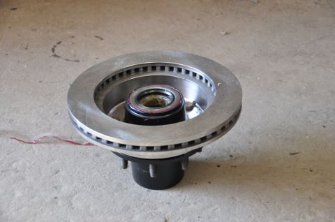 1996 Ford Bronco - A close-up view of a brake rotor and hub assembly, likely a replacement part, resting on a concrete surface.