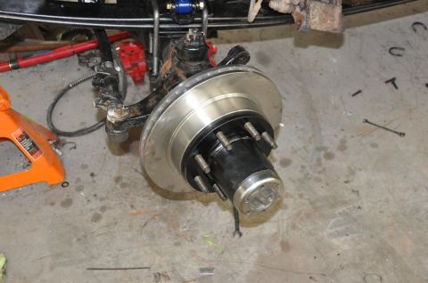 1996 Ford Bronco - The front wheel hub and brake assembly of a vehicle is shown in detail, resting on a concrete floor.
