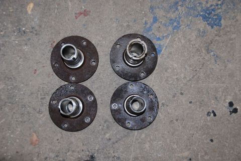 1996 Ford Bronco - Four used wheel hubs are laid out on a concrete surface, showing signs of rust and wear.