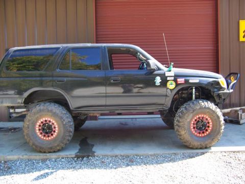 1992 Ford Mustang - Modified black SUV with oversized tires and aftermarket bumper parked in front of a garage door.