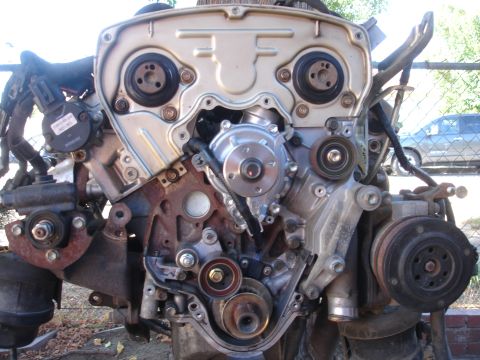 1993 Ford Taurus - Engine assembly with timing belt and water pump visible, with a car in the background.