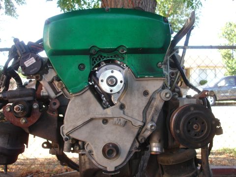 1993 Ford Taurus - This is a close-up view of an engine, focusing on the green-painted cover and surrounding mechanical parts.
