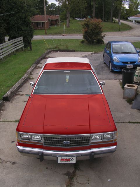 1988 Ford Crown Victoria LTD - Front view of a red 1988 Ford Crown Victoria LTD, parked next to a blue Honda Fit.
