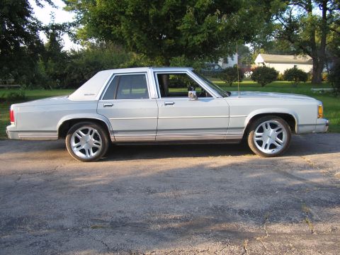 1988 Ford Crown Victoria LTD - A light-colored 1988 Ford Crown Victoria LTD is shown from the side, parked outdoors.