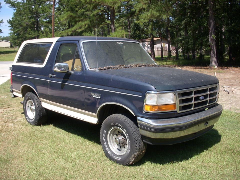 Dark blue and tan Ford Bronco SUV parked on grass, front 3/4 view