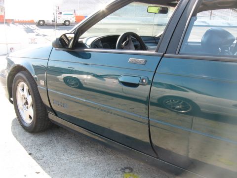 1993 Ford Taurus - The side of a green sedan is shown, with a reflection of its wheel in the door panel.