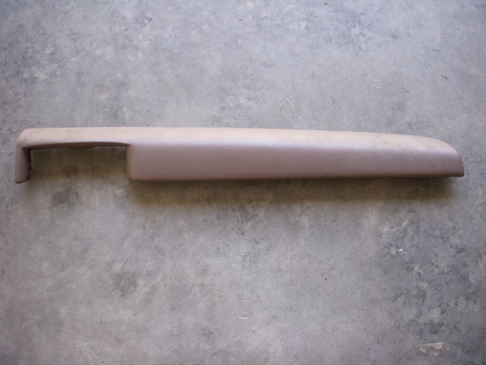 Tan dashboard trim piece on concrete floor