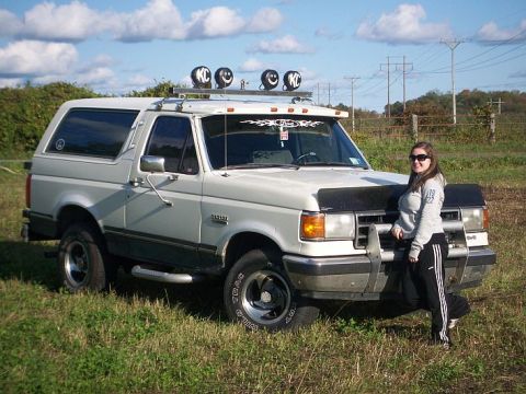 1991 Ford Bronco - A woman poses next to a 1991 Ford Bronco in an outdoor setting.