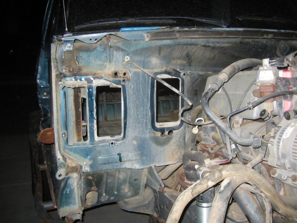Stripped engine bay of teal truck showing bare firewall, alternator and wiring