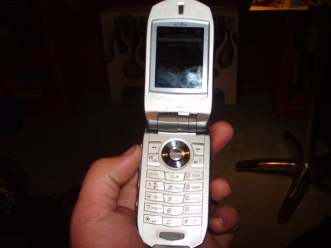 1995 Ford Bronco - A flip phone is held in a hand, with a blurry background.