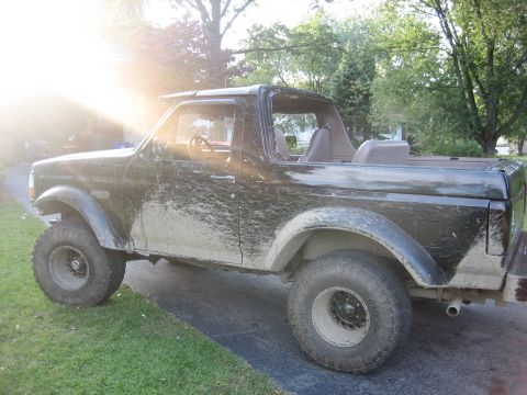 1995 Ford Bronco - This black SUV is covered in mud, suggesting it has been off-roading recently.
