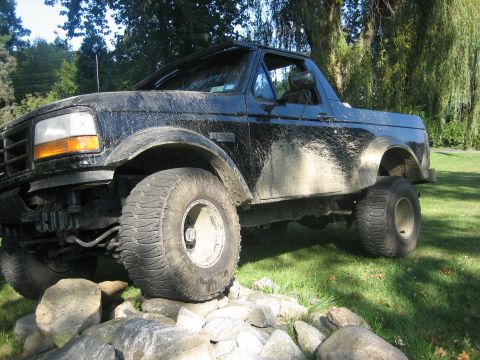 1995 Ford Bronco - This black 1995 Ford Bronco is covered in mud and appears to be navigating an obstacle course of rocks.