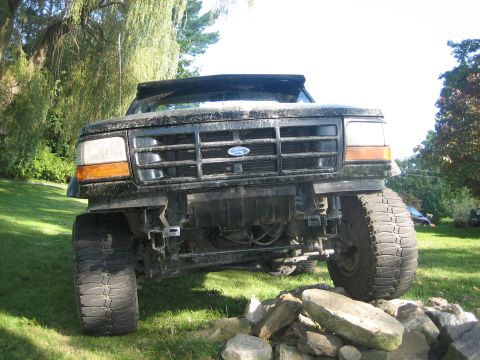 1995 Ford Bronco - Front view of a modified 1992 Ford Bronco with oversized tires, positioned on a rocky surface.