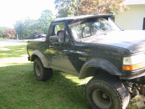 1995 Ford Bronco - This 1995 Ford Bronco is heavily covered in mud, suggesting recent off-road use.
