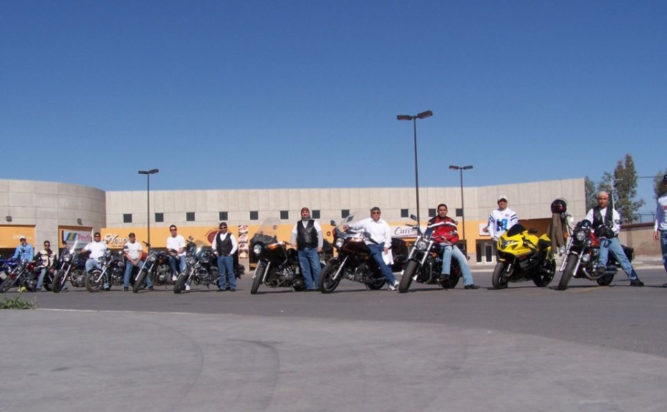 Riders lined up with cruiser and sportbike motorcycles in a sunny parking lot