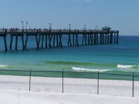 1973 Ford Ranchero - A pier juts out into the turquoise ocean, with people visible on its walkway.