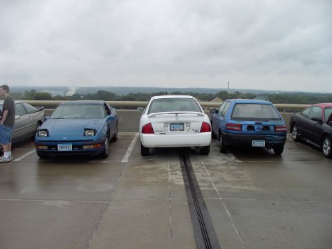 1989 Ford Probe - A blue 1989 Ford Probe is parked in a lot with other vehicles under a cloudy sky.