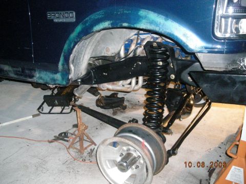 1993 Ford Bronco - A blue 1993 Ford Bronco is shown with its front suspension lifted and the wheel removed for modification.