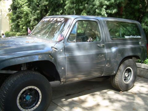 1986 Ford Bronco - Side view of a heavily modified SUV, likely for off-road use, with custom wheels and tires.