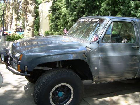 1986 Ford Bronco - A heavily modified pickup truck is parked outdoors, large tires and aftermarket modifications.