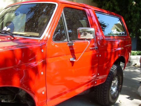 1986 Ford Bronco - This red SUV, likely from the 1980s, has a distinctive body style with visible rivets along its side panels.