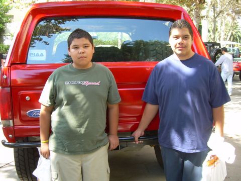 1986 Ford Bronco - Two boys pose with a red 1986 Ford Bronco at an outdoor event.
