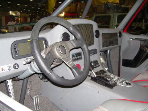 1986 Ford Bronco - The interior of a heavily modified off-road vehicle features a custom dashboard with a digital screen and racing-style shifter.