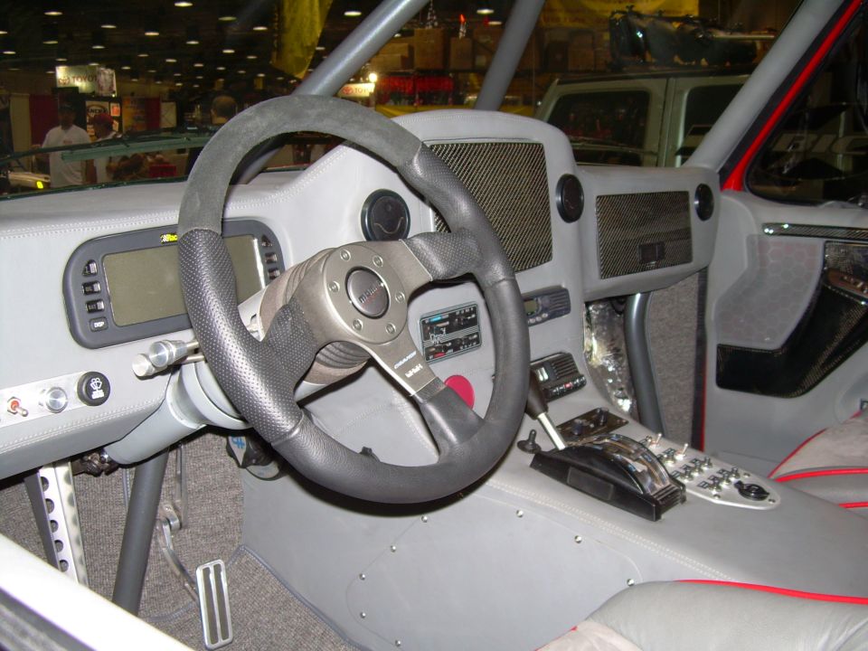 Custom off-road vehicle interior with aftermarket steering wheel, digital display, and shifter