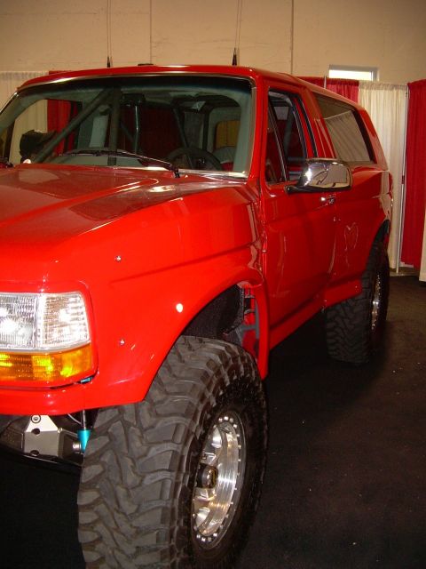 1986 Ford Bronco - This red SUV, possibly a 1992 Ford Bronco, features a prominent roll cage and off-road tires.