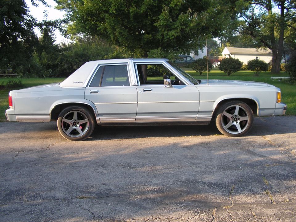 Light blue sedan with aftermarket wheels parked on asphalt