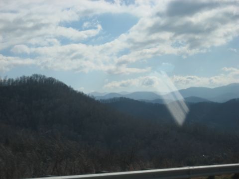 2001 Ford Crown Victoria - A scenic view of rolling mountains under a partly cloudy sky, captured from a moving vehicle.