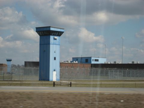 2001 Ford Crown Victoria - A view of a correctional facility guard towers and fenced perimeters under a cloudy sky.