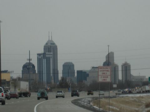 2001 Ford Crown Victoria - Traffic moves along a highway with a city skyline in the background on a cloudy day.