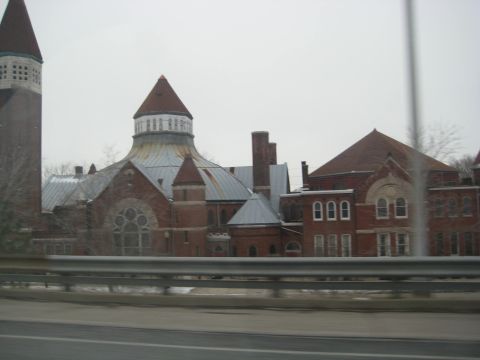 2001 Ford Crown Victoria - A large, old brick building complex with multiple architectural styles is visible under an overcast sky.