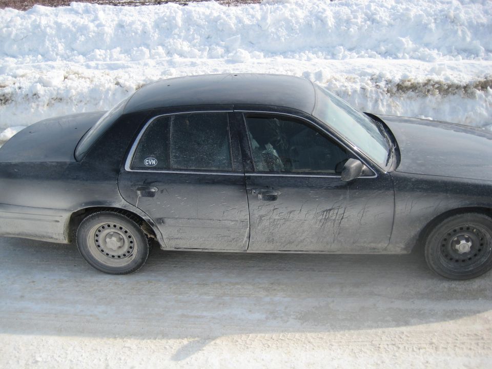 Side view of a black 2001 Ford Crown Victoria parked on a snowy road