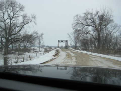2001 Ford Crown Victoria - The reflection of a dashboard is visible on a wet, snowy road as it curves towards a bridge in the distance.