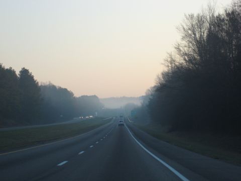 2001 Ford Crown Victoria - A foggy highway stretches into the distance with several vehicles on the road.